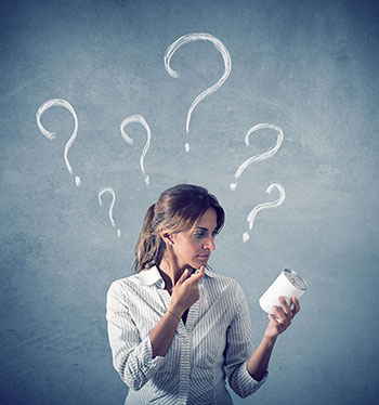 Photo of a woman looking uncertainly at a can she is holding