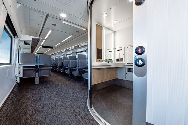 L’intérieur d’un train de voyageurs montrant l’intérieur d’une salle de bain accessible par l’ouverture de sa large porte qui se rétracte complètement